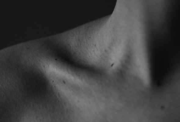 Black and white photo of a woman's shoulder, collarbone and neck
